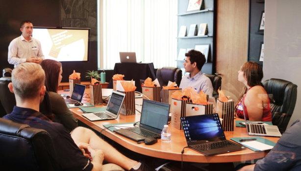 man-standing-in-front-of-people-sitting-beside-table-with-laptop-computers.jpg man standing in front of people sitting beside table with laptop computers